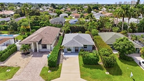 A residential area with houses, a driveway, and a well-maintained lawn. - Beach-Inspired Naples Park Home | Heated Pool (Naples)