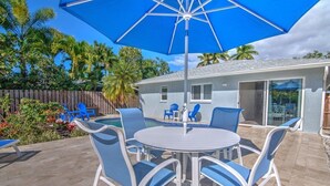 An outdoor patio with a round table and chairs, a blue umbrella, and a pool area. - Naples Park House w/Heated Pool, Near Beaches (Naples)