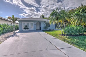 A single-story house with a garage, a driveway, and a well-maintained lawn with palm trees.