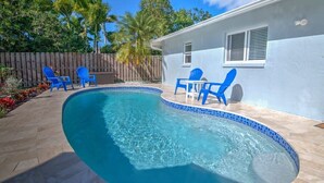 A swimming pool with blue chairs and a wooden fence in the background. - Naples Park House w/Heated Pool, Near Beaches (Naples)