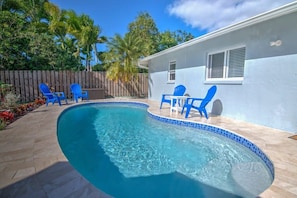 A swimming pool with blue chairs and a wooden fence in the background. - Naples Park House w/Heated Pool, Near Beaches (Naples)