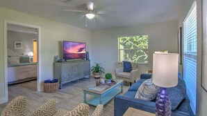 A living room with a television, sofa, armchair, and a ceiling fan. - Naples Park House w/Heated Pool, Near Beaches (Naples)