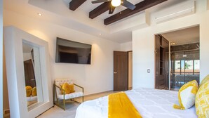 Een moderne slaapkamer met een groot bed, een aan de muur bevestigde televisie en een inloopkast.