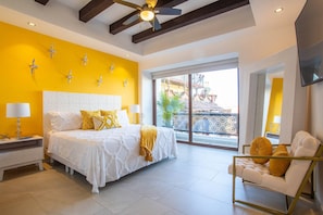A bedroom with a bed, bedside tables, a sofa, and a balcony with a view.