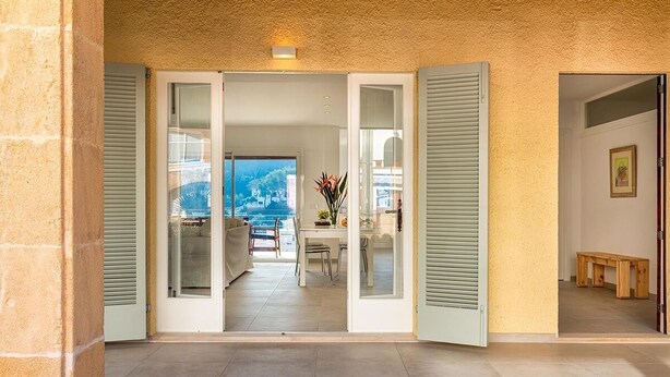 Ein geräumiges Entree mit Blick auf einen Balkon, einen Essbereich und eine hölzerne Bank.