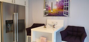 Cozy living space with refrigerator, table, and comfortable armchairs.