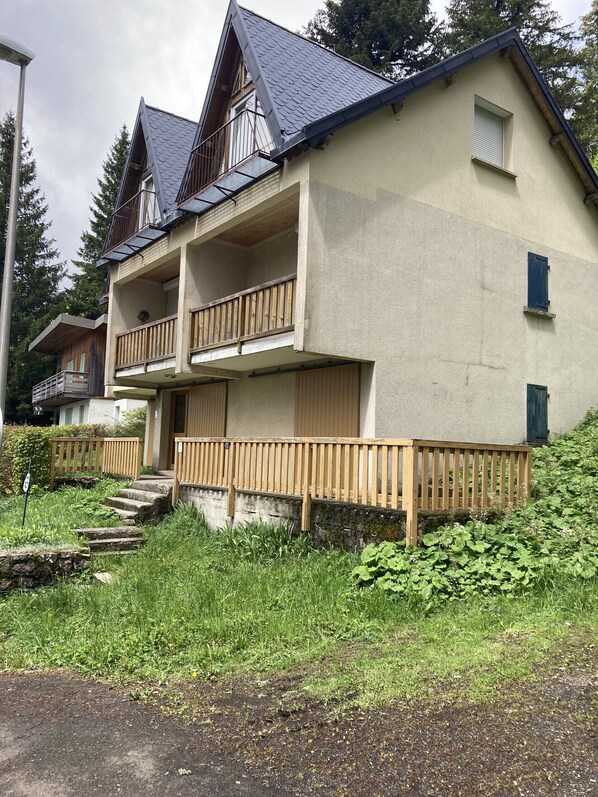 Un edificio de dos pisos con un balcón, una ventana pequeña y una valla de madera.