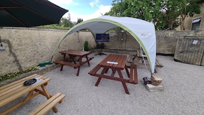 Un espacio de estar al aire libre cubierto con mesas de picnic y una carpa.