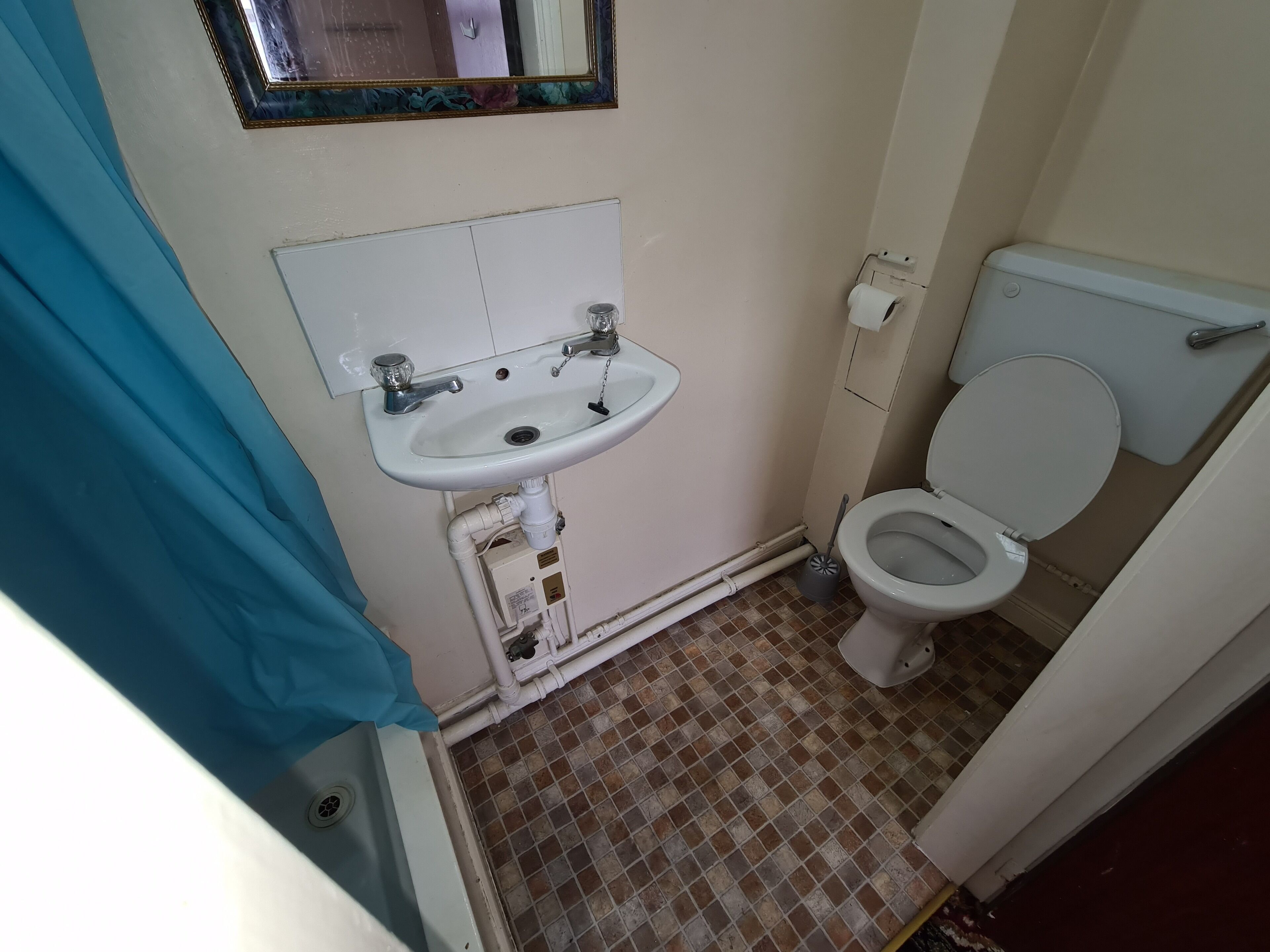 Un baño pequeño con un lavamanos blanco, un inodoro y un espejo sobre el lavamanos.
