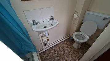 Un baño pequeño con un lavamanos blanco, un inodoro y un espejo sobre el lavamanos.