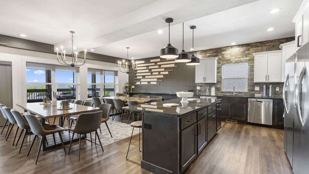 A modern kitchen with a central island, stainless steel appliances, and a dining area with a large table and chairs. - Westview - Indoor pool & lake views (Branson)
