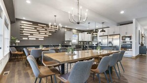 A modern kitchen with a large dining table, built-in appliances, and a chandelier. - Westview - Indoor pool & lake views (Branson)