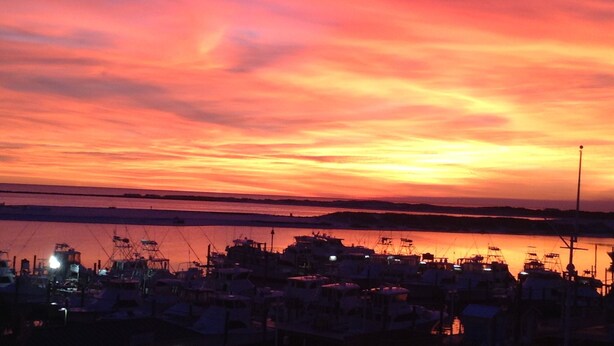 A marina at sunset with boats docked and a clear sky.