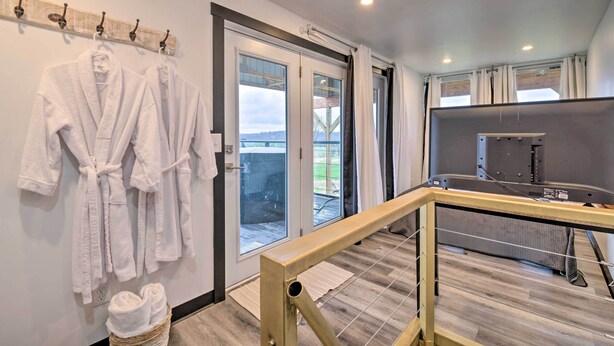 Un baño moderno con cabina de ducha de vidrio, piso de madera y toallero con toallas blancas.