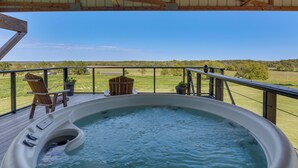 Un jacuzzi en una terraza con vistas a un paisaje verde.