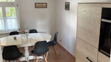 A dining area with a round table, black chairs, and a white cabinet with a black oven.