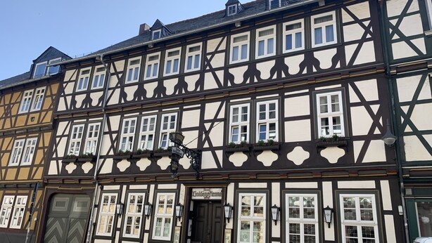 A traditional half-timbered building with multiple windows, a door, and a sign indicating a restaurant. - Hotel Goldene Krone (Goslar)