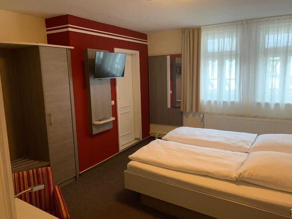 Ein Hotelzimmer mit zwei Betten, einem an der Wand befestigten Fernseher und einem Kleiderschrank.