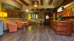 A hotel lobby with striped armchairs, a wooden reception desk, and a large painting on the wall. - Hotel Goldene Krone (Goslar)