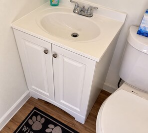 Une salle de bain avec un lavabo, un meuble et des toilettes, le tout de couleur blanche.