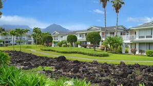Un resort con edificios de varios pisos, césped cuidado y un primer plano rocoso.
