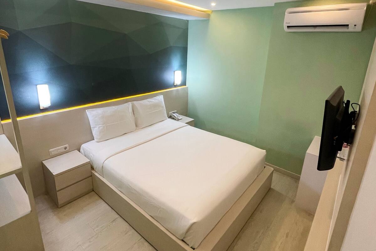 Een moderne slaapkamer met een groot bed, nachtkastjes, een airconditioning en een kledingkast.