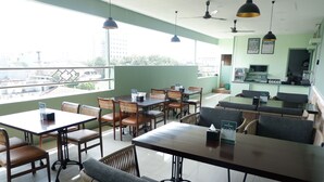Un restaurante con mesas, sillas, una barra y vistas a edificios.