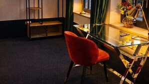 A modern room with a glass desk, red chair, and a TV mounted on the wall. - Sleephotels Suite Garde (Hamburg)