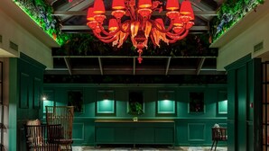 Un hall d’entrée spacieux, agrémenté d’un magnifique lustre, de murs verts et d’un sol en marbre.