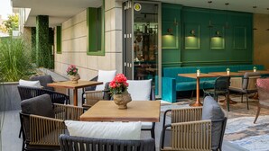 Un espace extérieur aménagé avec des meubles en osier, un mur végétal et une porte en verre donnant accès à un espace intérieur.