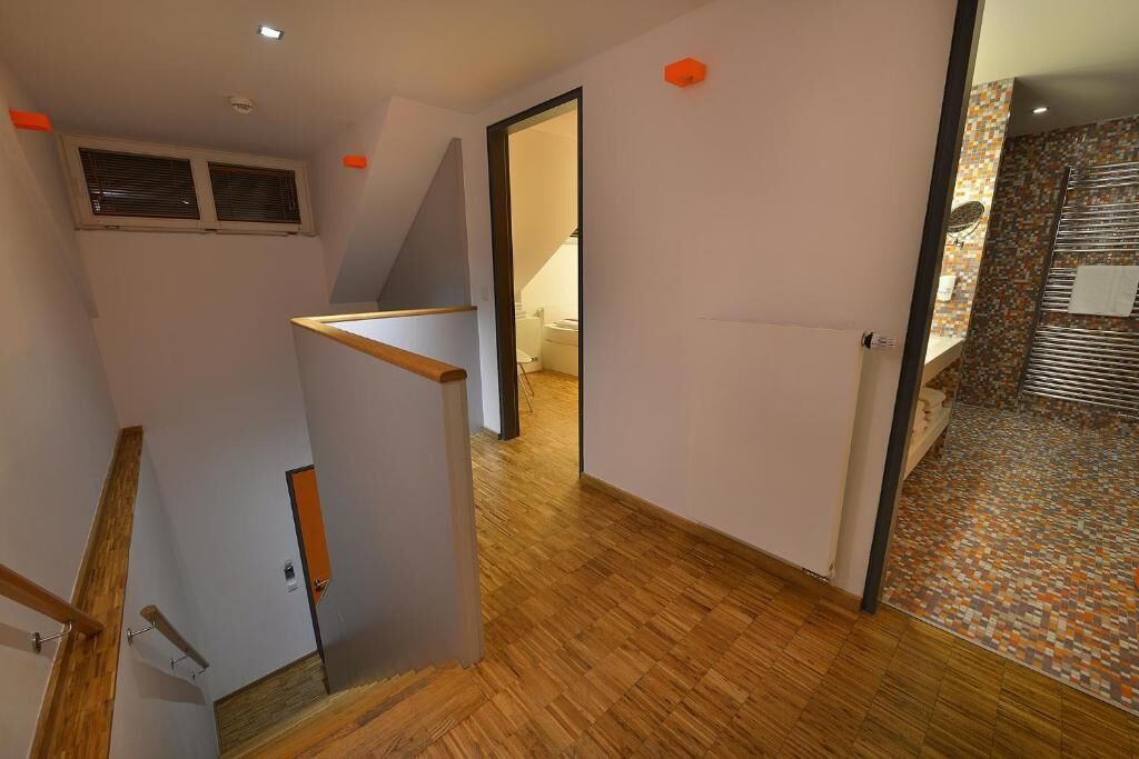 A hallway with wooden flooring, a staircase, and a bathroom with a tiled shower area.