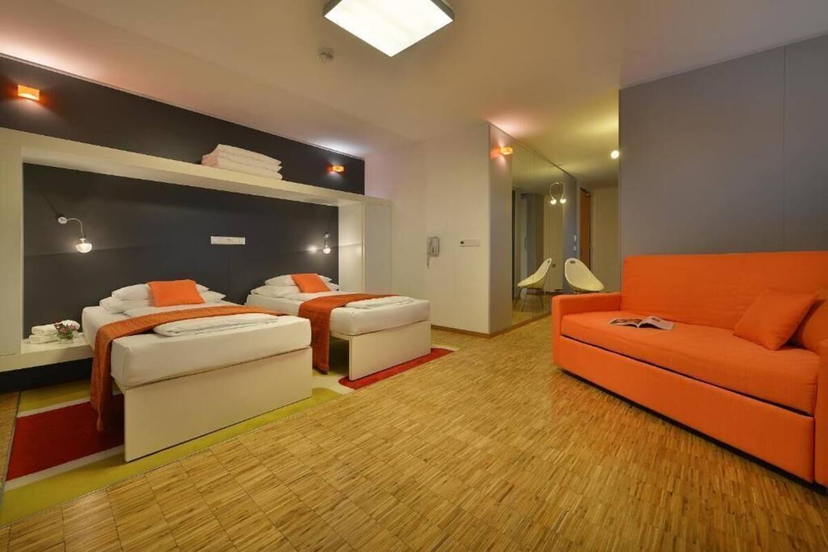 A modern room with a bed, two seating areas, a sofa, and a mirror.