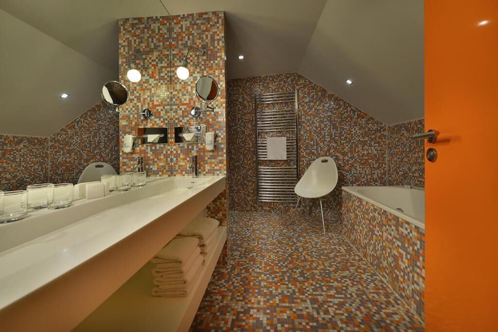 Un baño moderno con suelo de baldosas, un espejo grande, un lavabo blanco y una bañera.