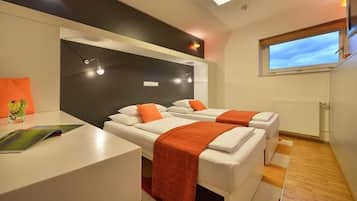 Une chambre moderne avec deux lits, un bureau et une fenêtre.