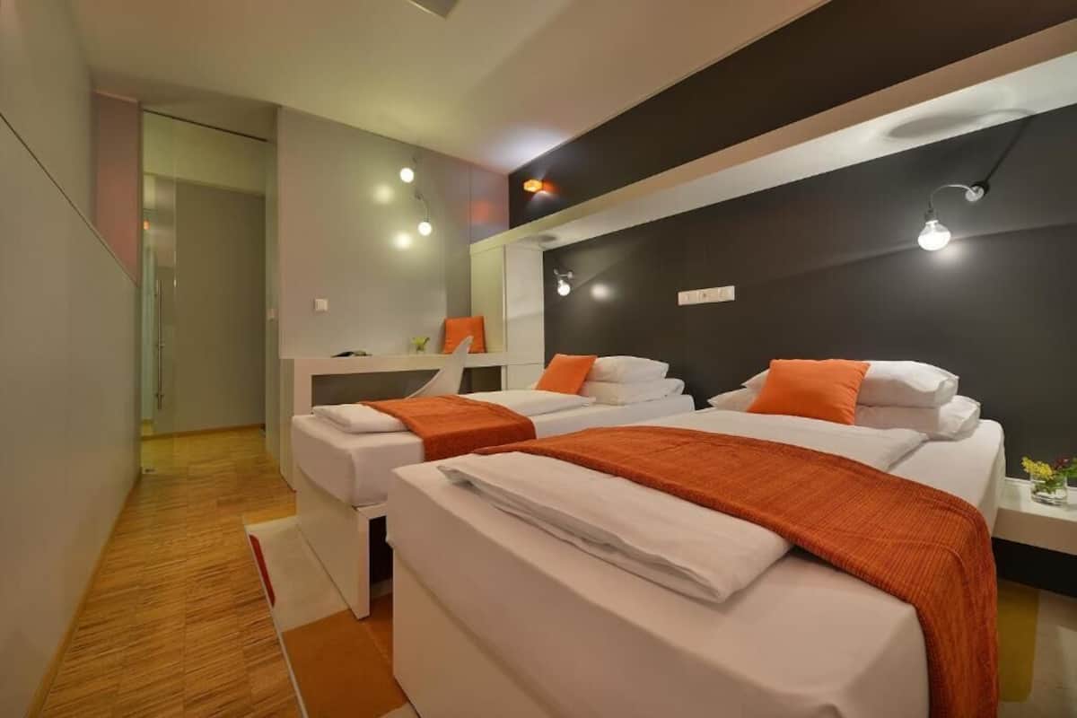 A hotel room with two beds, a small desk, and a mirror.