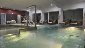 An indoor swimming pool with lounge chairs and a changing room. - Omnia Hotel Relax & Wellness (Janske Lazne)