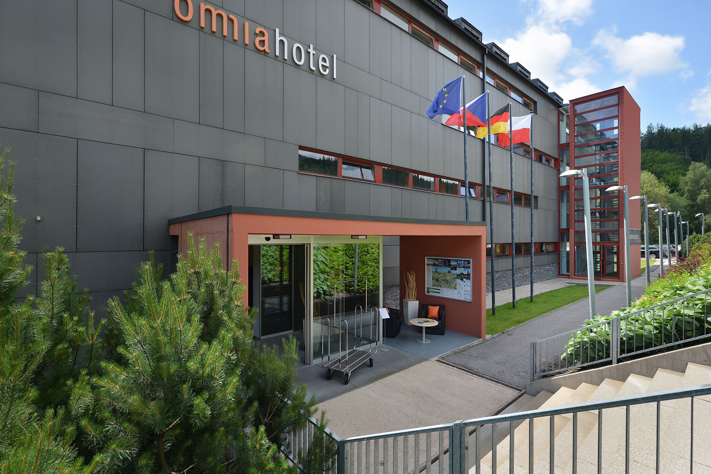 Moderni rakennus, jossa on kyltti, jossa lukee »Omnia Hotel», ja useita lippuja, mukaan lukien Euroopan unionin lippu.