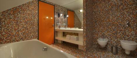 A bathroom with a large bathtub, two sinks, and a tiled backsplash.