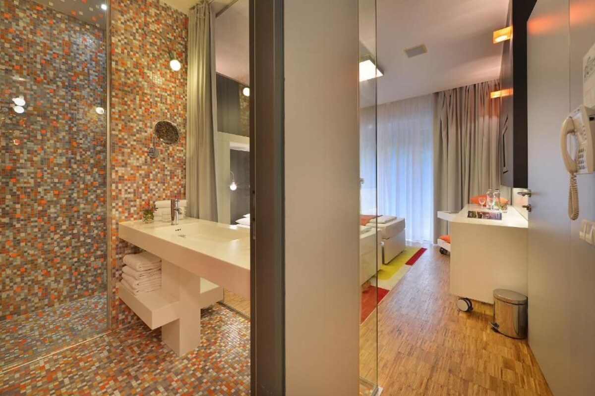 Een moderne badkamer met een betegelde muur, een wit wastafeltje en een douchehoek.