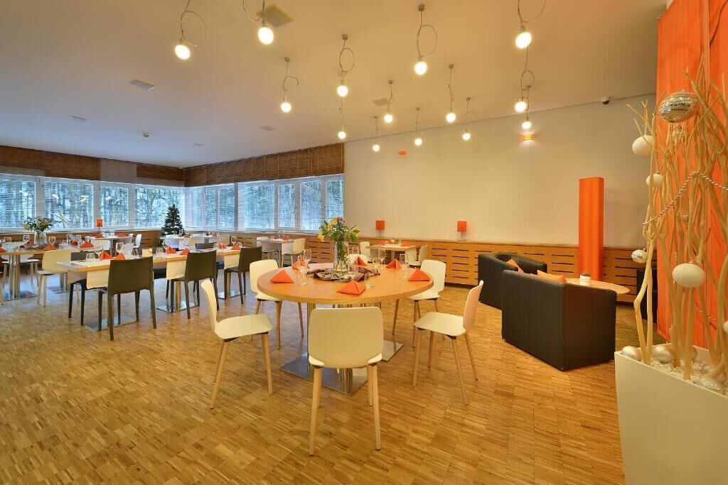 A spacious dining area with multiple tables and chairs, large windows, and modern lighting fixtures.