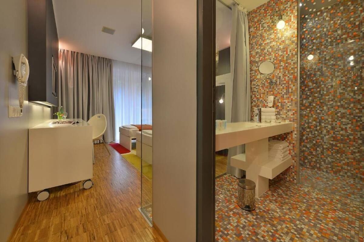 A modern bathroom with a tiled shower, a white sink, and a glass partition.