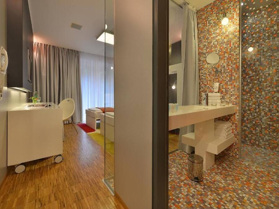 A modern bathroom with a tiled shower, a white sink, and a glass partition.