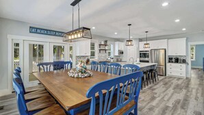 Una cocina amplia con armarios blancos, una mesa de comedor de madera y sillas azules.
