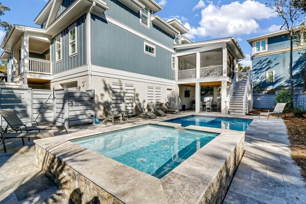 A two-story house with a pool, outdoor seating, and a covered porch.