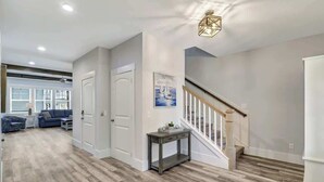 Un amplio salón con suelo de madera, una escalera y una zona de comedor con mesa y sillas.