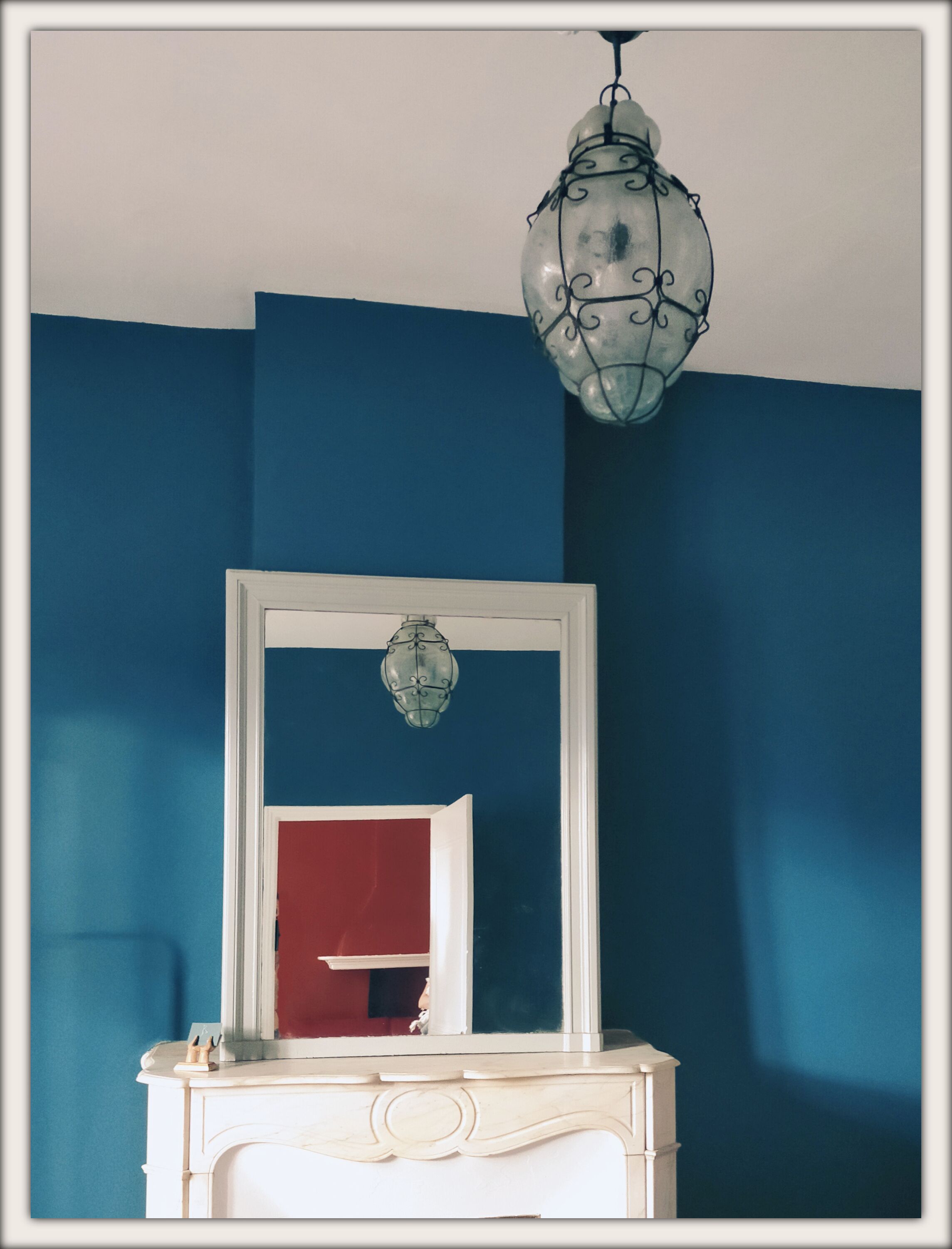 Una habitación con un tocador blanco, un espejo y una pared azul.