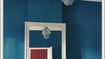 Una habitación con un tocador blanco, un espejo y una pared azul.
