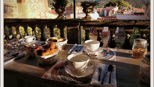 A table set for breakfast with croissants, bread, and a jar of nuts, overlooking a mountainous landscape. - La Belle D'Âme (Prades)