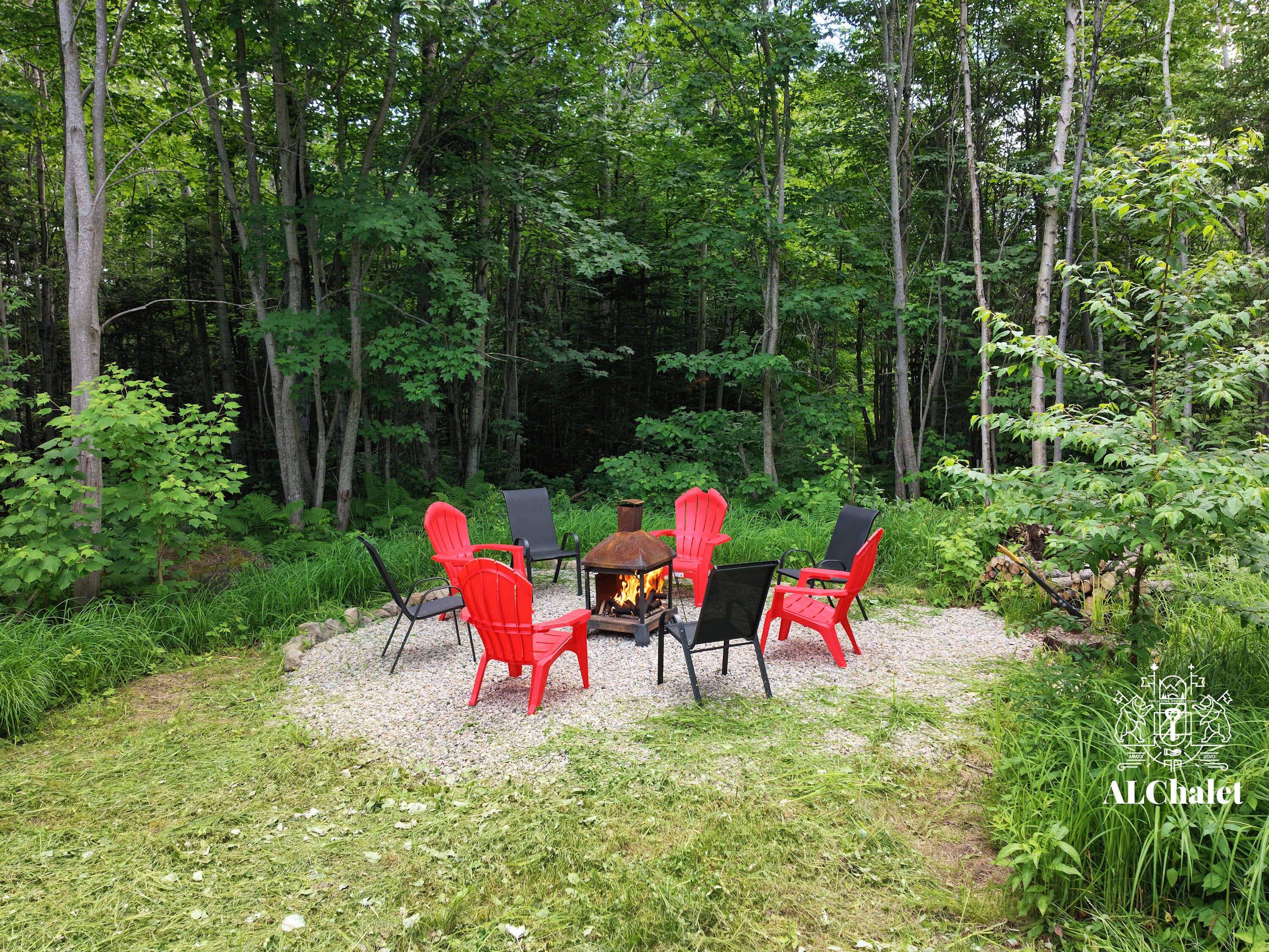 A forested outdoor area with a fire pit and seating.