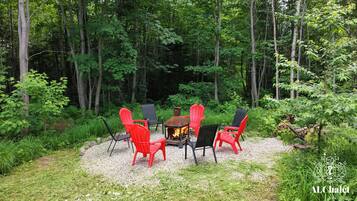 A forested outdoor area with a fire pit and seating.